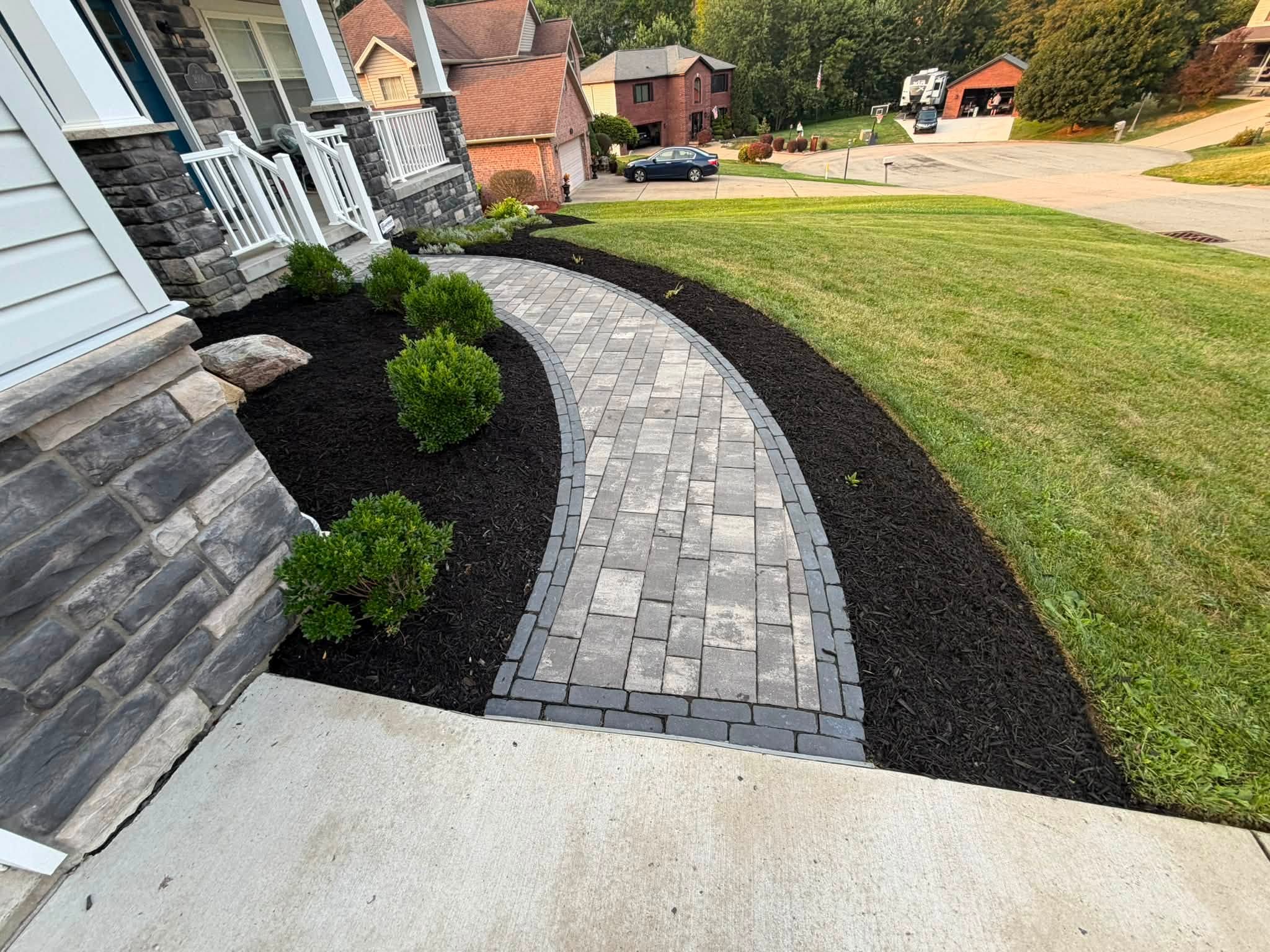 Defined black mulch beds and trimmed shrubs beside a curved walkway